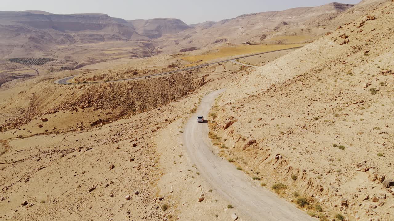 Un'auto percorre una strada polverosa attraverso il terreno desertico accidentato della Riserva della Biosfera di Dana