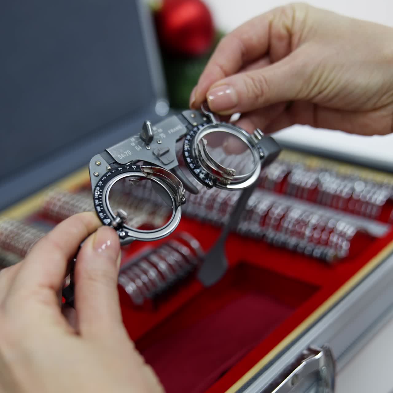 Doctor selecting lenses to the trial frame. Hands of female optometrist picking up test lenses from case for eyesight examination Close-up