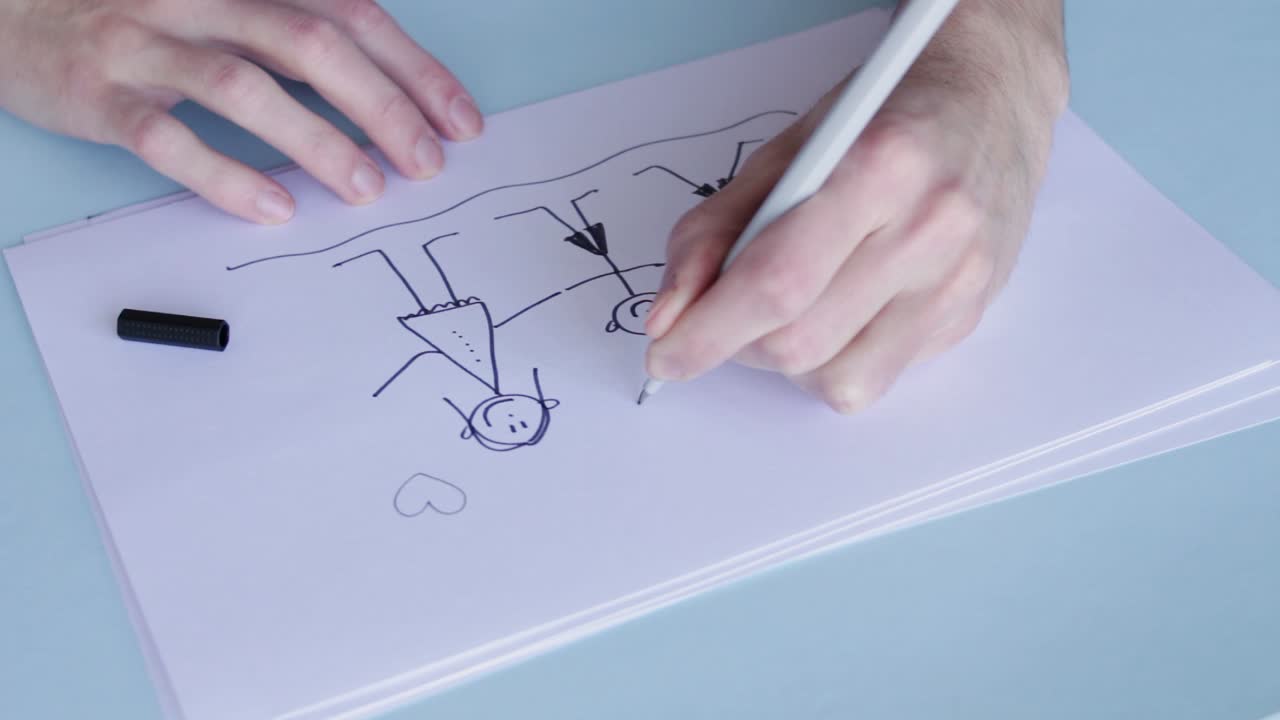 사람이 흰 종이에 함께 들고 있는 가족의 막대기 그림 위에 마음을 그립니다.