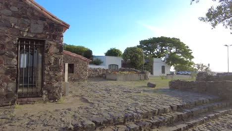 antigua casa de piedra colonial junto al río con una brillante puesta de sol