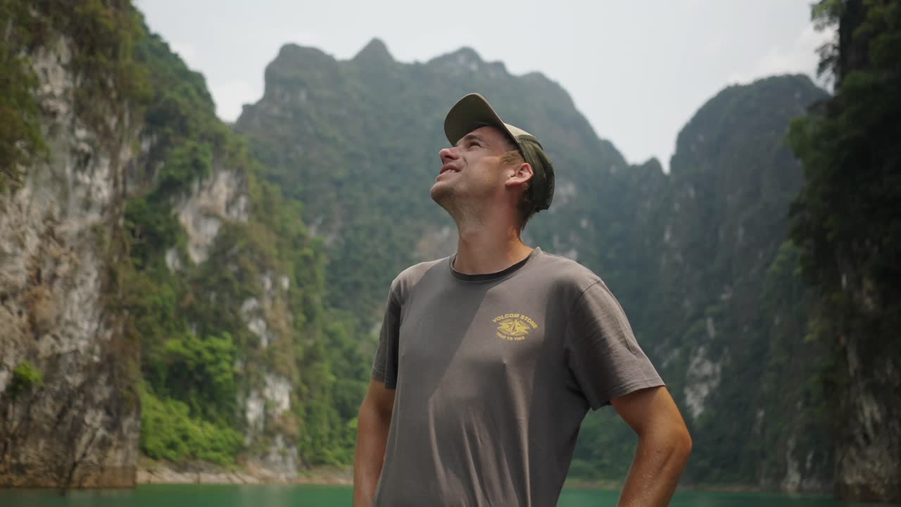 Man looking up at majestic limestone karsts on a scenic lake