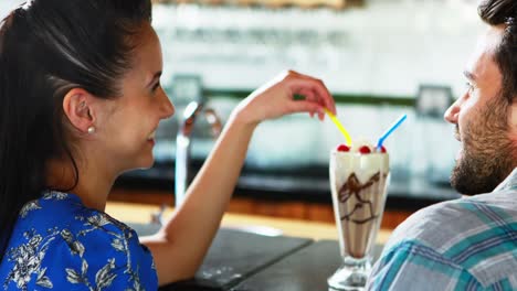 pareja feliz interactuando mientras tienen batido de leche