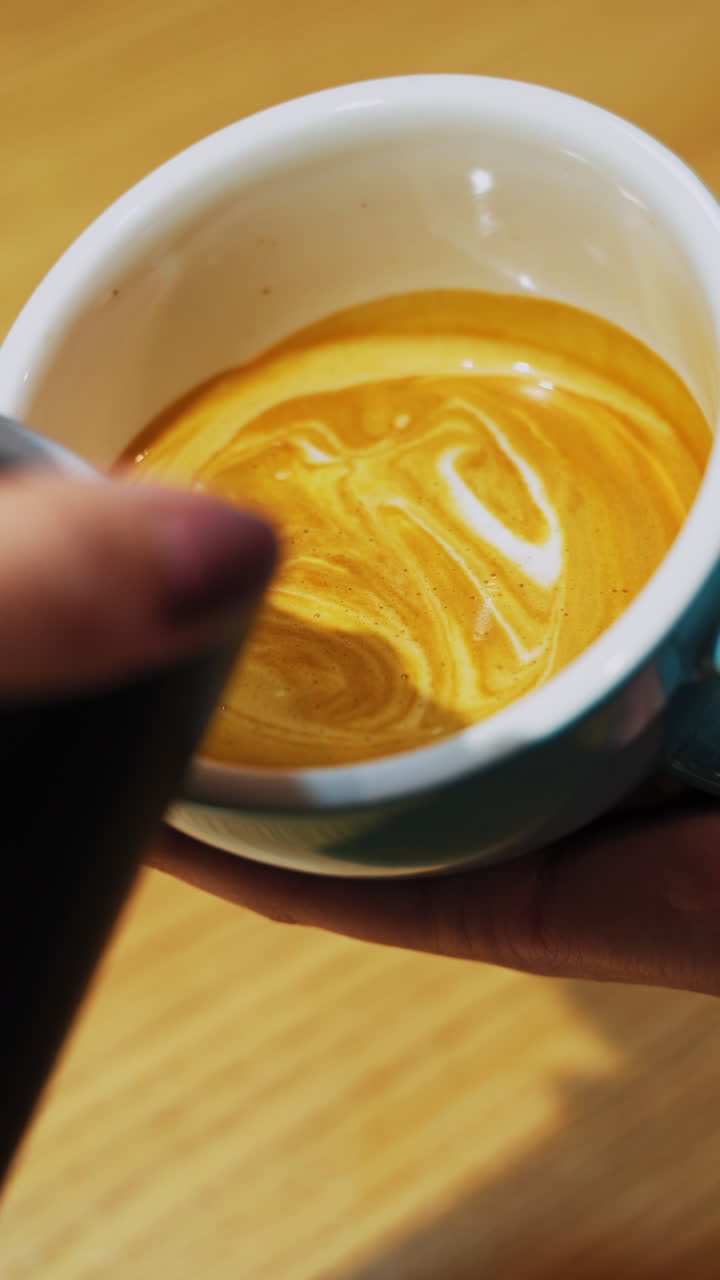 Female hands pouring milk. Professional barista pouring steamed milk into coffee cup