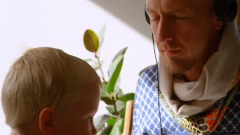 father and children listening to music on headphones at home 4k