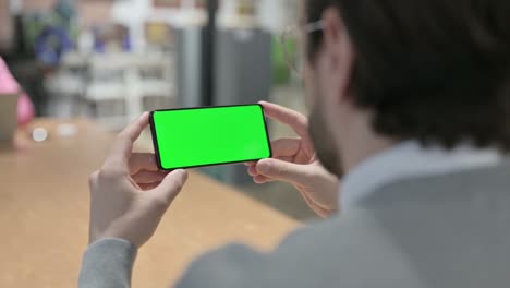hombre mirando un teléfono inteligente con pantalla de croma verde
