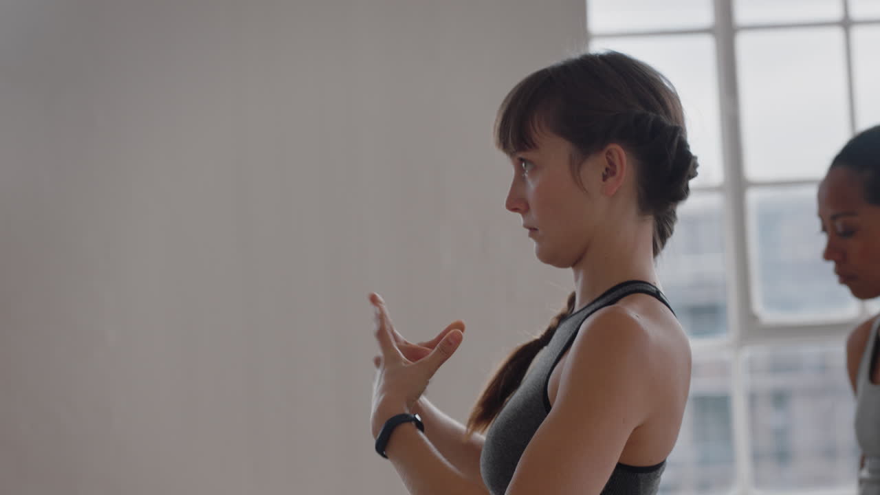 hermosa joven en clase de yoga practicando gestos con las manos aprendiendo poses preparándose para hacer ejercicio en el gimnasio