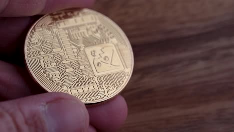 the reverse side of a physical bitcoin being held with a wooden background