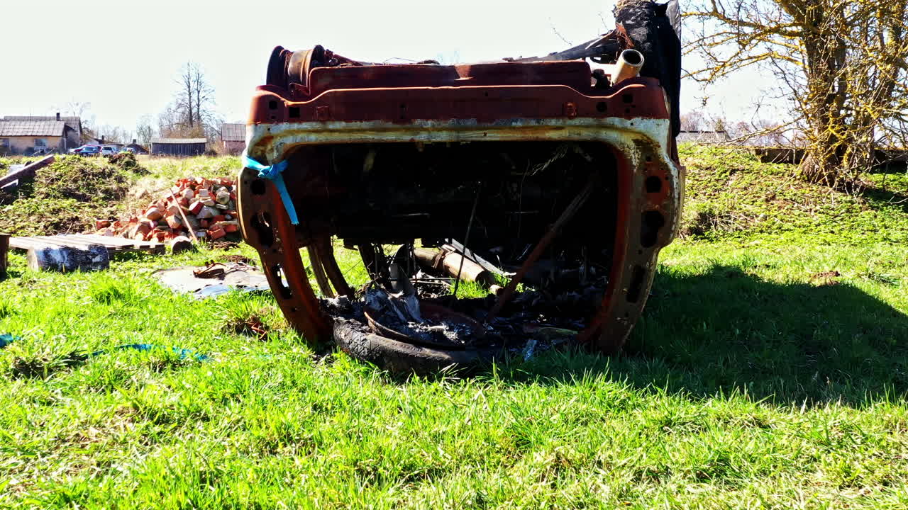 Burned undercarriage of flipped car showing fire damage and exposed vehicle components