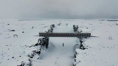 Person-Running-On-Frozen-River-Under-The-Bridge-Between-Continents-In-Reykjanes-Peninsula,-South-Iceland