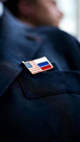 Close-up of a lapel pin featuring the American and Russian flags on a suit jacket
