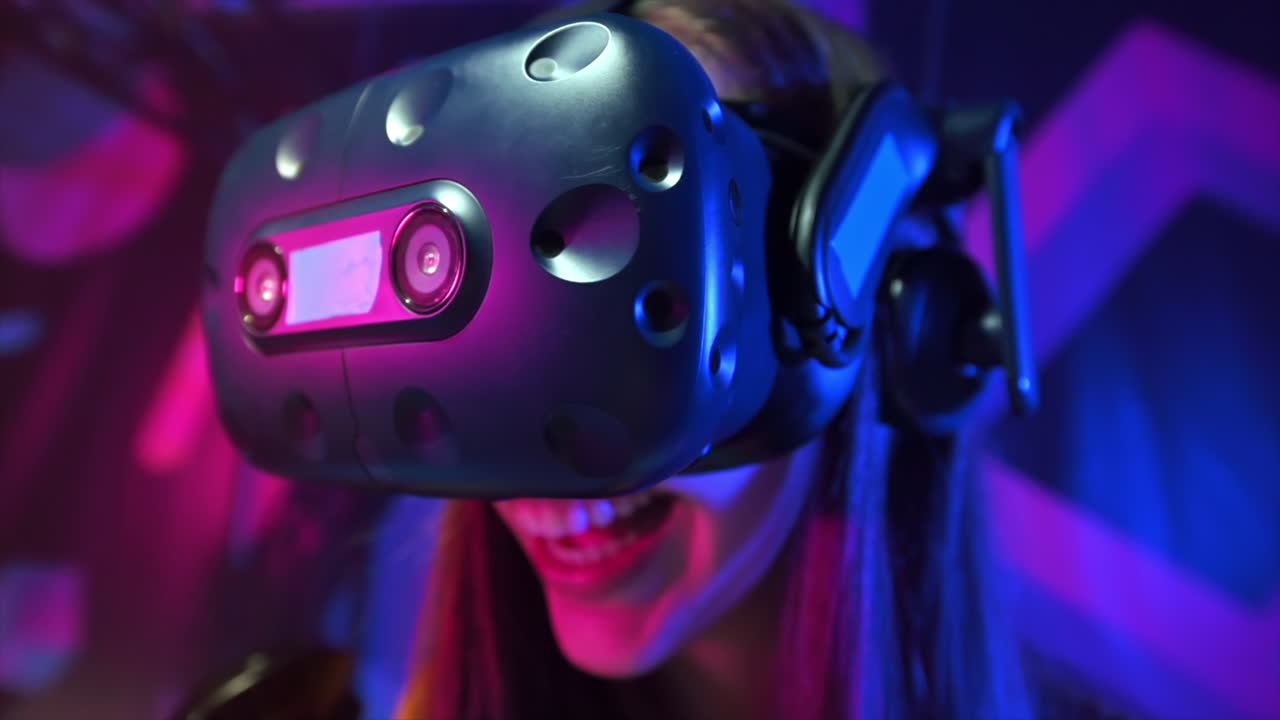 Primo piano di una ragazza felice e sorpresa che gioca su un tapis roulant VR usando casco e controller. Rallentatore