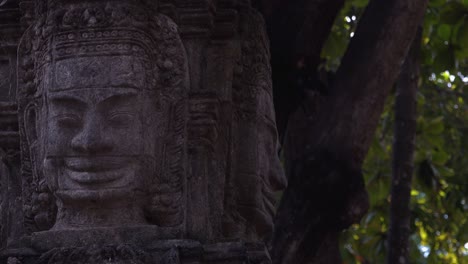 slider shot showing khmer stone statue with trees in the background