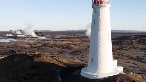 geothermal park with clouds of gas flying past iceland lighthouse, aerial