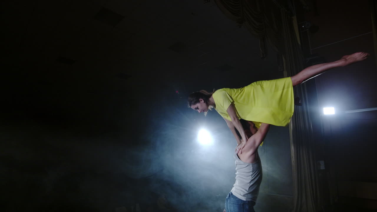 Zoom camera a female dancer jumps onto her partner shoulder. Acrobatic dance musical on stage in smoke. Contemporary