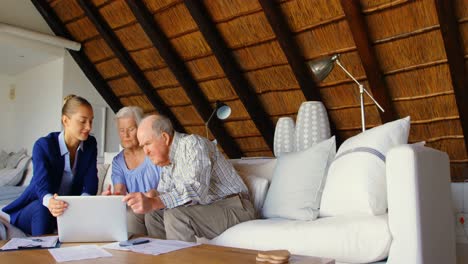 front view of caucasian senior couple discussing over clipboard with female doctor at comfortable co