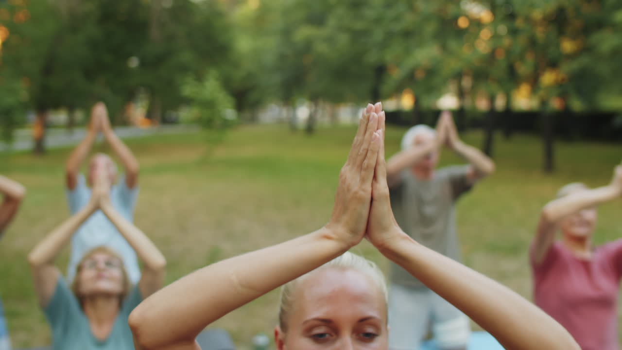 mujer dirigiendo una clase de yoga al aire libre en el parque