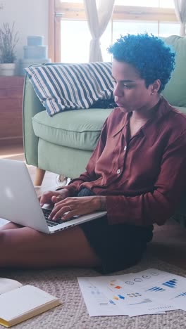 young casual african american woman freelancer uses laptop sits on floor in home