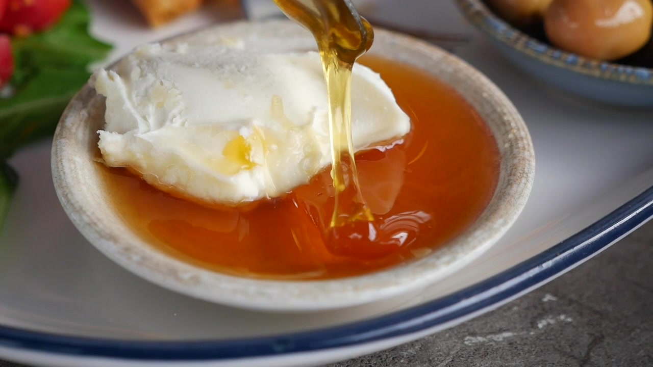 Miele che cola su formaggio cremoso fresco in una piccola ciotola