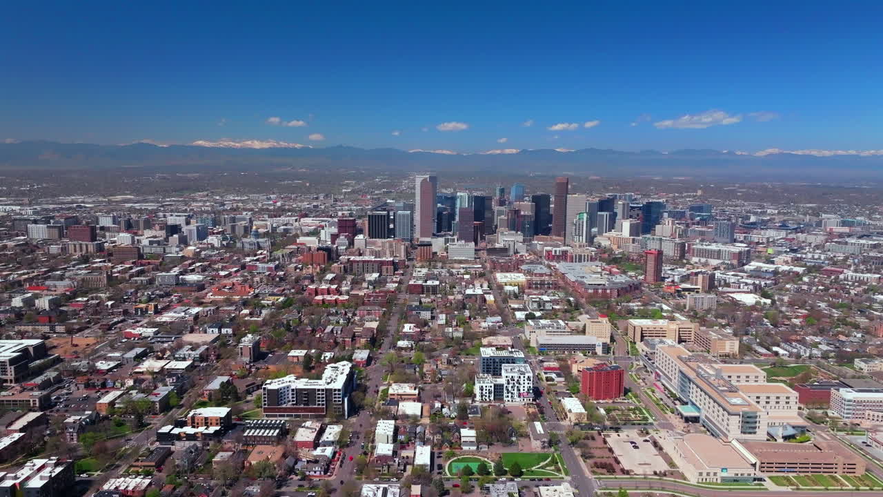 Front range Lodo Downtown Denver cityscape Rocky Mountain Landscape spring summer City Park Washington Park aerial drone Colorado street tall buildings skyscrapers cars sunny blue sky backwards motion