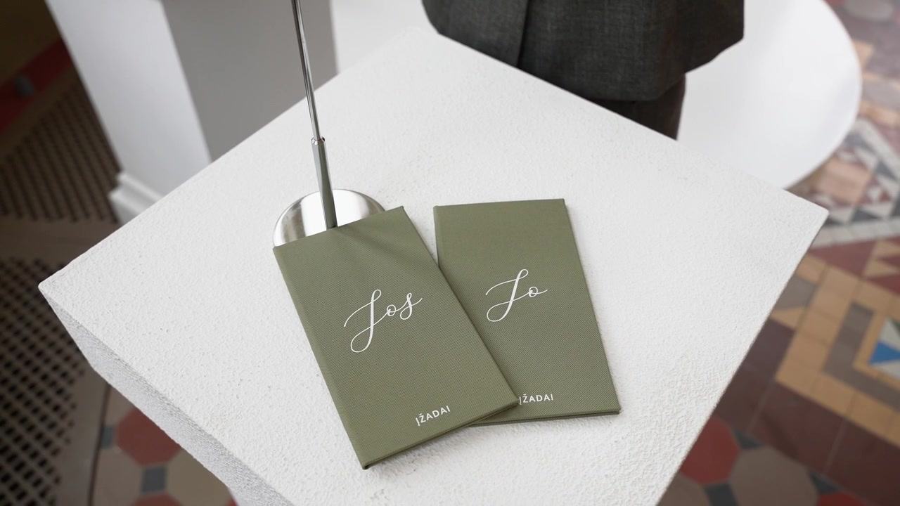 Close-up shot of elegant olive green 'Yes' and 'No' vote cards on a white pedestal at a civil ceremony, with geometric tiled flooring and natural light for a modern, stylish mood.