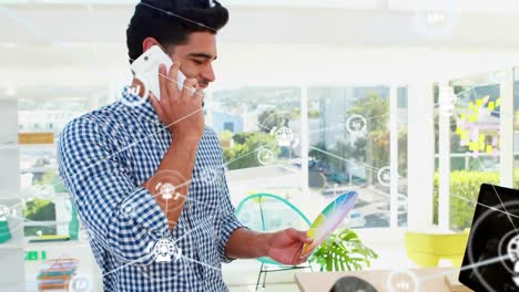 animation of data processing with networks and icons over biracial businessman using smartphone