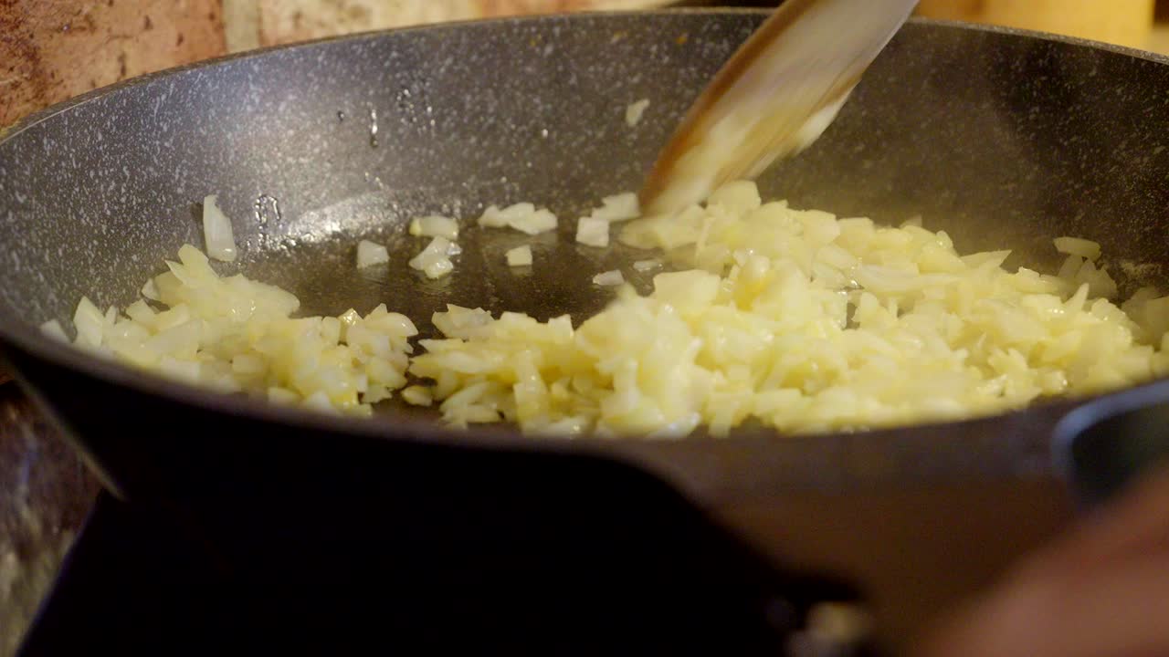 Sautéed onions being stirred by a chef while preparing breakfast