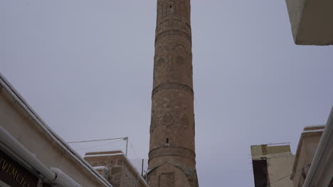 Colocada-En-El-Histórico-Bazar-De-Mardin,-La-Cámara-Revela-La-Grandeza-Del-Minarete-De-La-Gran-Mezquita-Al-Escanearlo-De-Abajo-Hacia-Arriba