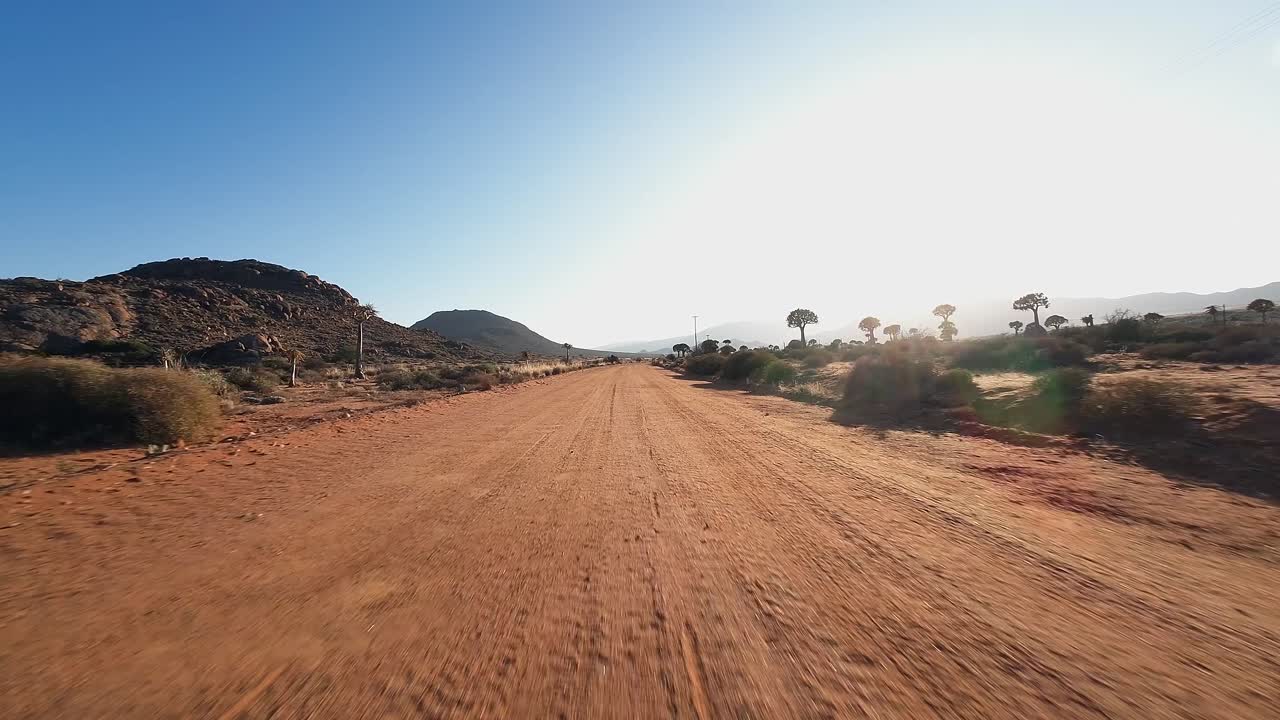 Driving plate POV: Low angle driving fast on golden dirt desert road