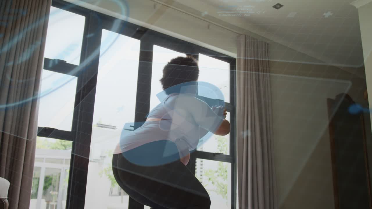 Woman performing guided squat routine in home fitness area, tablet cueing blue overlay guiding form