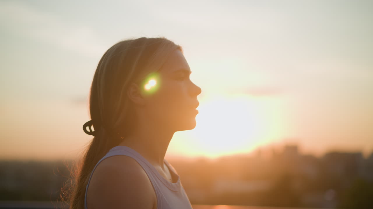 vista lateral de una joven caminando al aire libre con expresión enfocada, luz esmeralda reflejándose en su cabello bajo la cálida luz del sol, creando un efecto de silueta contra un fondo suave