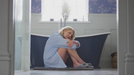 Menopausal-Mature-Woman-Suffering-With-Incontinence-Sitting-On-Bathroom-Floor-At-Home