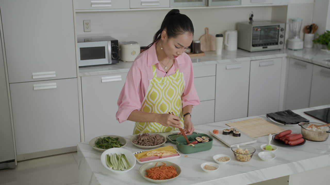 Asian Housewife Putting Self-made Kimbap in Lunch Box at Kitchen