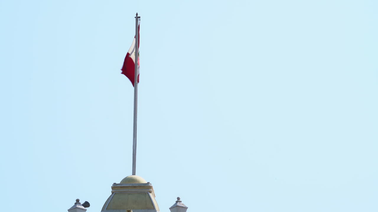 Closeup footage of Peru flag waving on Municipal Palace at Chiclayo, Peru during daytime.
