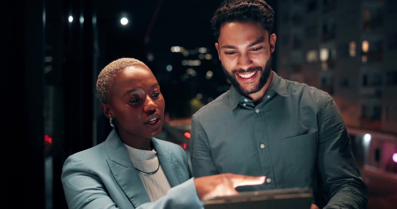 Diverse Business Colleagues Discussing Project on Tablet at Night