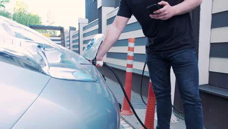 proceso de reabastecimiento de combustible de un automóvil eléctrico. un disparo debajo de la escotilla donde se carga el automóvil ecológico eléctrico. la escotella de carga del automóvil eléctrico se abre automáticamente. una mano masculina inserta un automóvil erecto