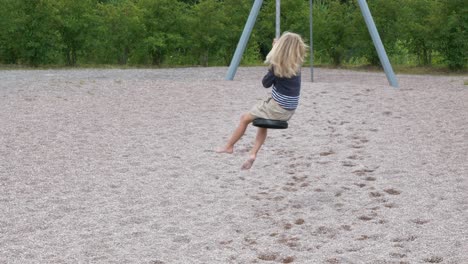 young blond girl plays with zip line at playground, slow motion shot