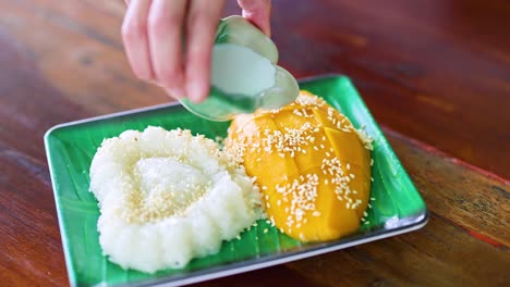 pouring coconut milk over mango sticky rice