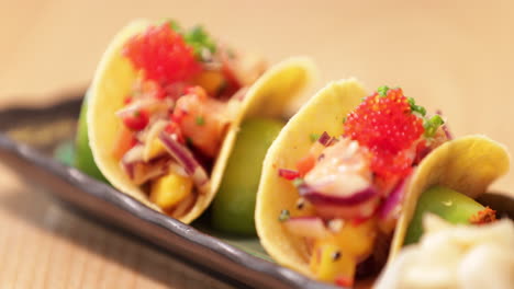 colorful sushi in crispy taco shells on a rectangular plate - slow motion pan right