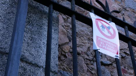 panning right to reveal a spiked gate with a "dogs forbidden" sign in spanish