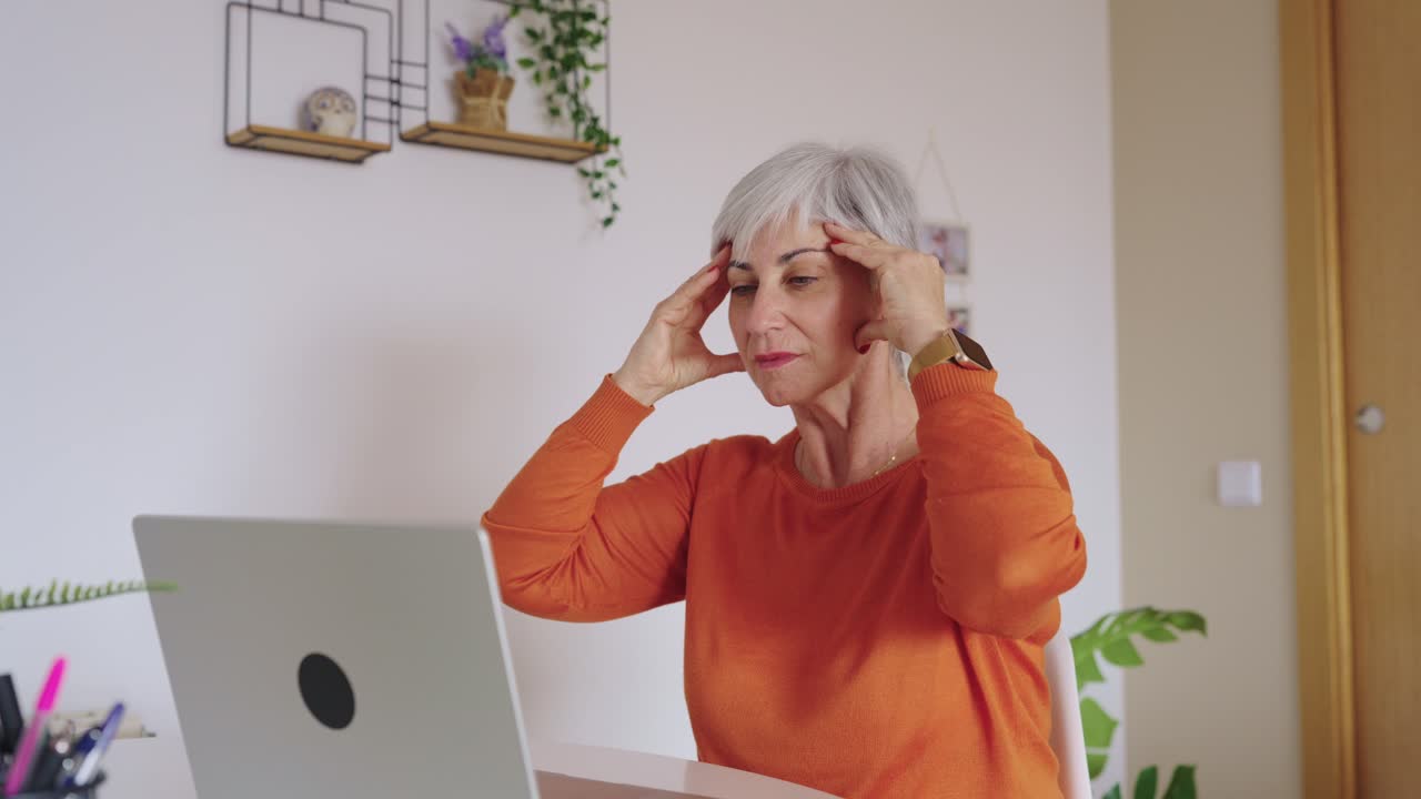 Senior Woman Experiencing Headache While Working on Laptop at Home