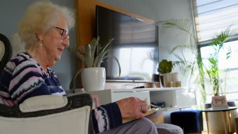 senior woman reading a book in living room 4k