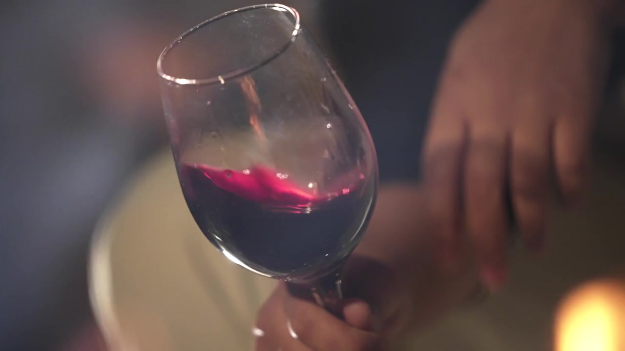 Vino rosso volteggia delicatamente in un bicchiere tenuto vicino a un fuoco ardente, creando un'atmosfera accogliente e intima a Mendoza, Argentina