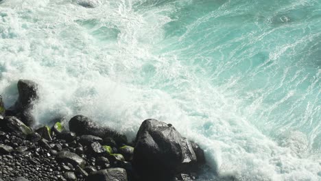 Rocky-beach-with-pebbles-and-ocean-waves,-slow-motion