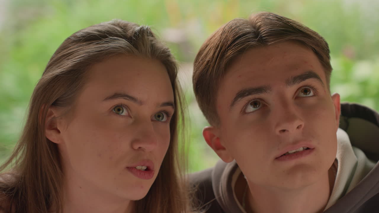 primo piano di una ragazza adolescente e un ragazzo adolescente con sguardo pensieroso in un giardino rigoglioso, un duo ambizioso che pianifica un progetto futuro e si scambia sguardi di speranza, luce naturale soffusa, connessione di supporto e sorrisi accennati