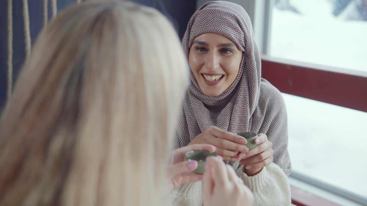 두 여인이 카페에서 차를 마시며 대화하고 있다