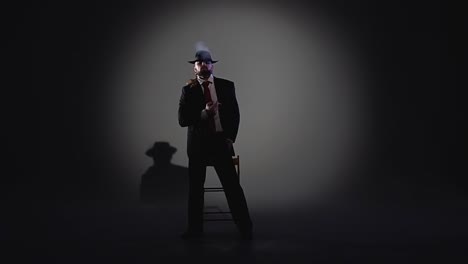 man in suit and hat standing on stage under spotlight