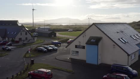 static drone shot of the uhi college campus, featuring the nearby wind turbine, a track and football pitch, and the neighbouring dark island hotel