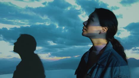 woman visiting immersive art exhibition interacting with images of clouds and mountains being projected onto her body