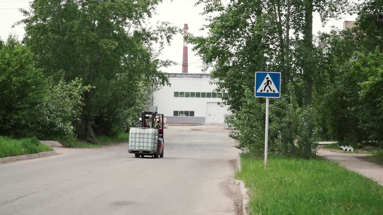 보행자 교차 표지판이 있는 산업 구역에서 재료를 운반하는 포크리프트