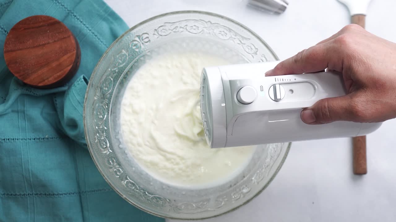 Making a dessert called Red Raspberry Tea Cake made with fresh berries and vanilla buttercream frosting. Great for Tea Parties. Using a white hand held electric mixer to blend together the cake batter